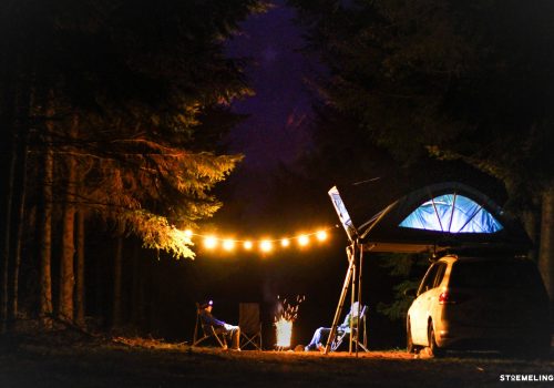 camping de nuit avec une tente de toit 4 places familiale en foret avec une guirlande et un feu dans un brasero stoemelings